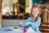 Очаровательная маленькая девочка обедает в кафе на открытом воздухе |  Премиум Фото